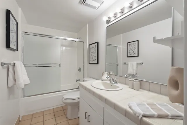 a bathroom with a granite countertop sink toilet and shower