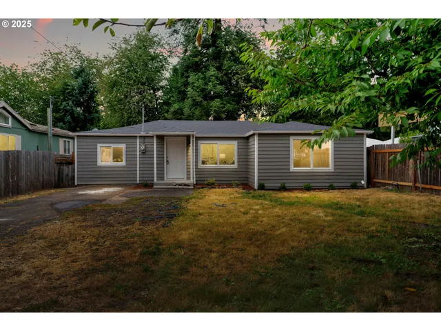 a backyard of a house with large trees and wooden fence