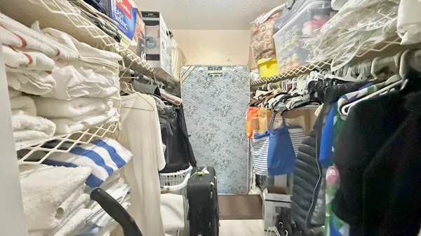 a view of walk in closet with clothes and shoes