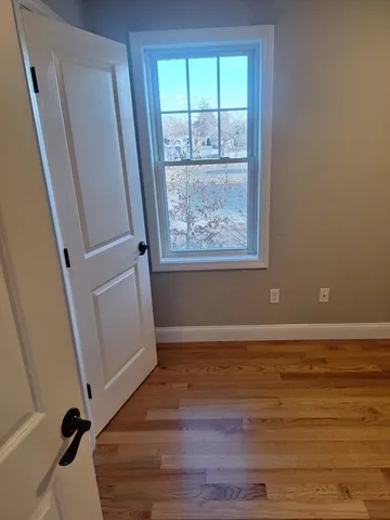 a view of an empty room with wooden floor and a window