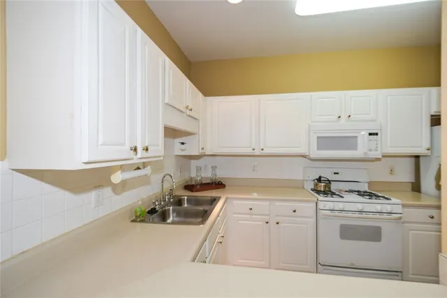 a kitchen with granite countertop a sink a stove and cabinets