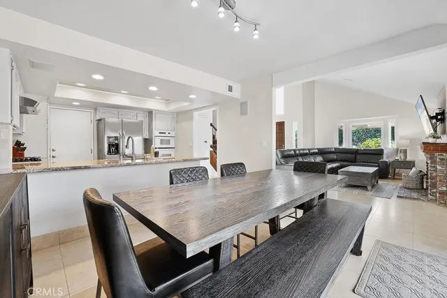 a dining hall with stainless steel appliances furniture large window and wooden floor