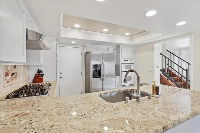 a view of a kitchen with kitchen island a sink stainless steel appliances and living room