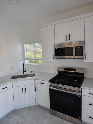 a kitchen with white cabinets and black appliances