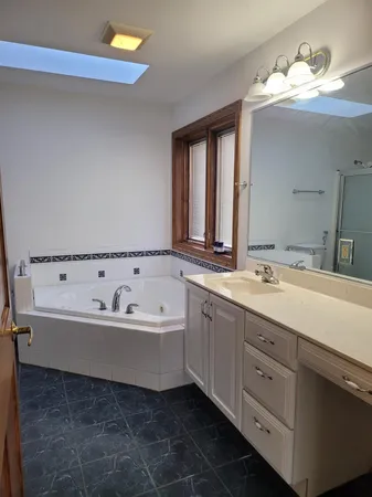 a spacious bathroom with a bathtub double sink and mirror