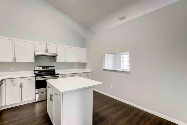 a kitchen with a stove cabinets and wooden floor