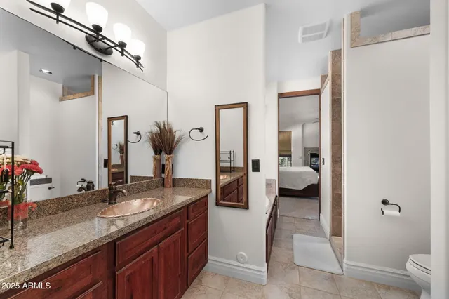 a en suite bathroom with a granite countertop sink and a mirror