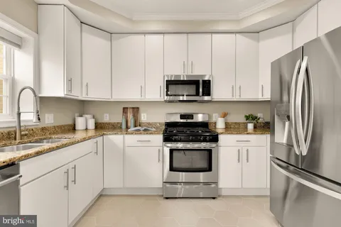 a kitchen with stainless steel appliances granite countertop a refrigerator stove a sink and dishwasher with white cabinets