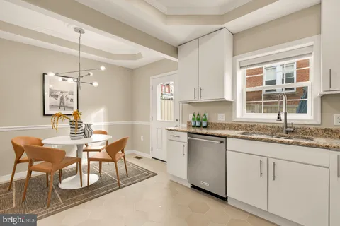 a kitchen with granite countertop sink window and white cabinets