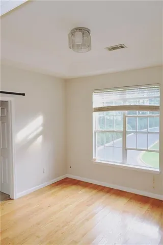 an empty room with wooden floor and windows