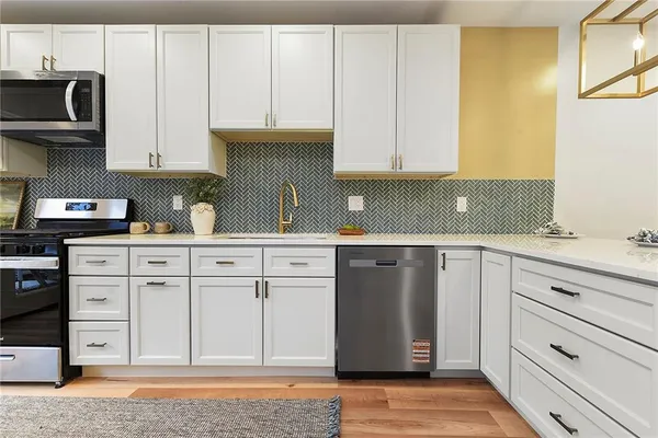 a kitchen with white cabinets and sink