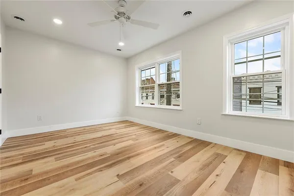 a view of empty room with wooden floor and fan