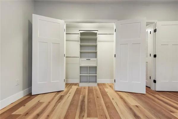 a view of empty room with wooden floor and closet