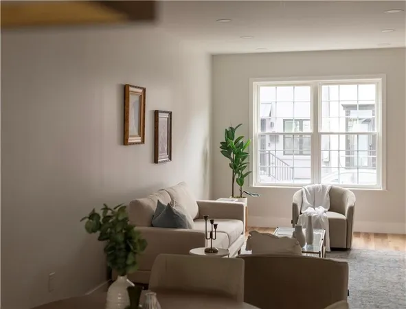 a living room with furniture and a potted plant next to a window