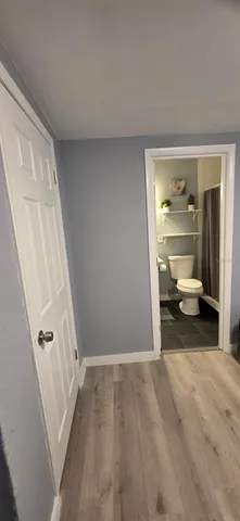 a view of an empty room with wooden floor and closet