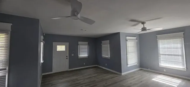 a view of an empty room with window and wooden floor