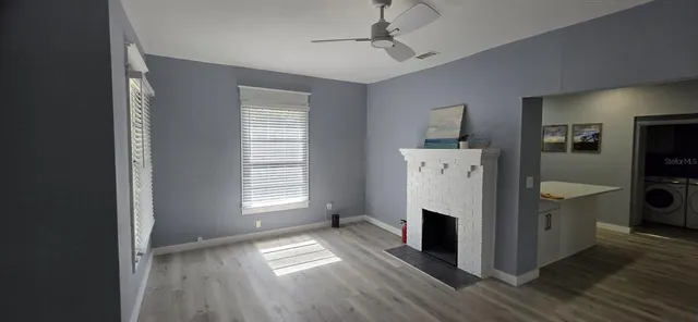 a view of a livingroom with a fireplace wooden floor and windows
