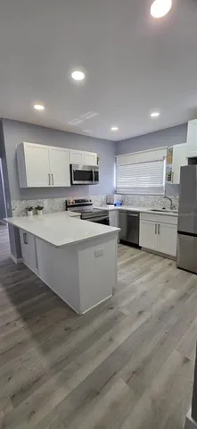 a large kitchen with stainless steel appliances lots of counter space and wooden floors