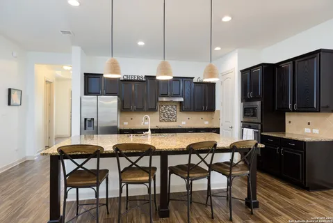 a kitchen with stainless steel appliances kitchen island granite countertop a table chairs refrigerator and microwave