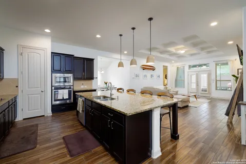 a kitchen with stainless steel appliances granite countertop a sink a stove and a wooden floors