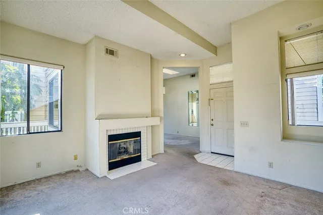 a view of an empty room with a fireplace and a window