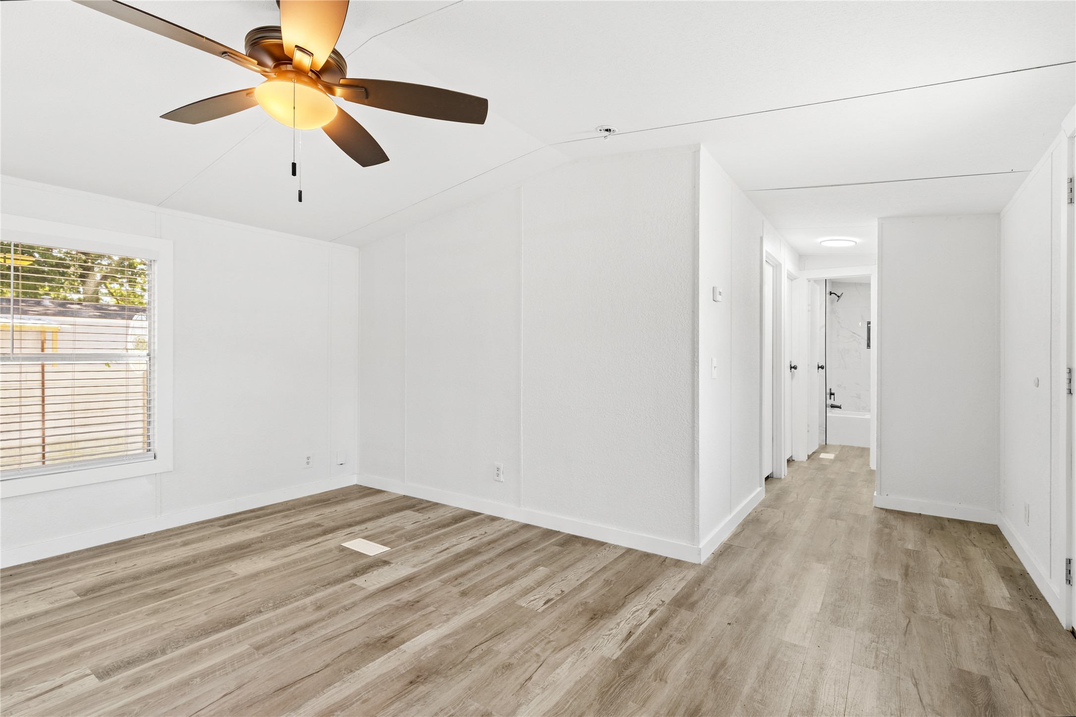 2134 County Road 5017 Cleveland, TX 77327 - Photo 8 of 25 an empty room with wooden floor fan and windows