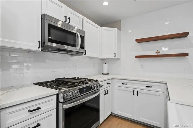 a kitchen with stainless steel appliances white cabinets and a stove top oven