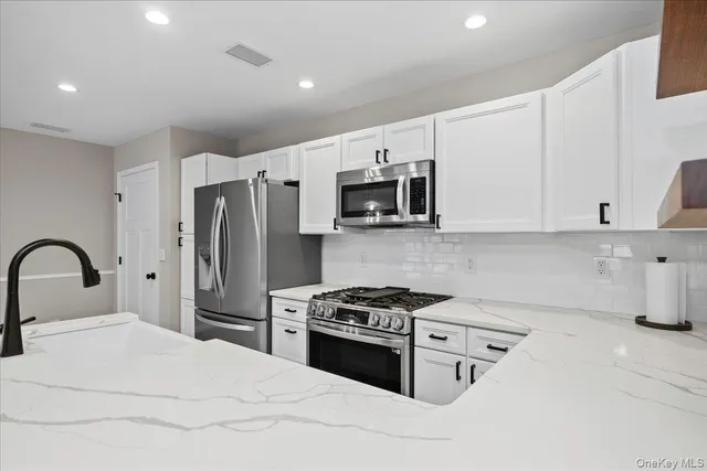 a kitchen with stainless steel appliances kitchen island a white cabinets and refrigerator