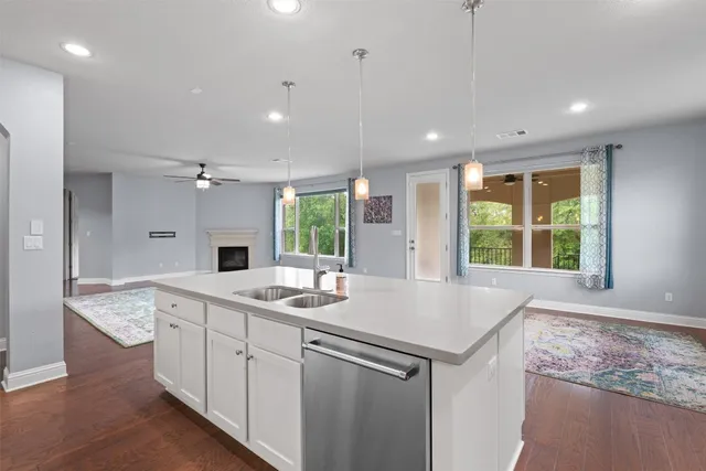 a kitchen with stainless steel appliances granite countertop a refrigerator a sink dishwasher a oven and white cabinets with wooden floor