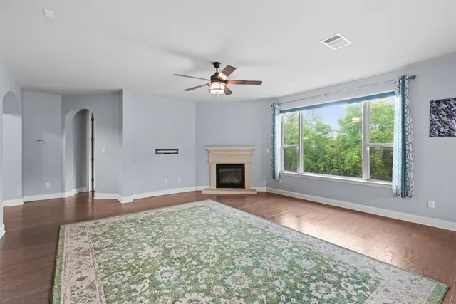 an empty room with wooden floor chandelier and windows