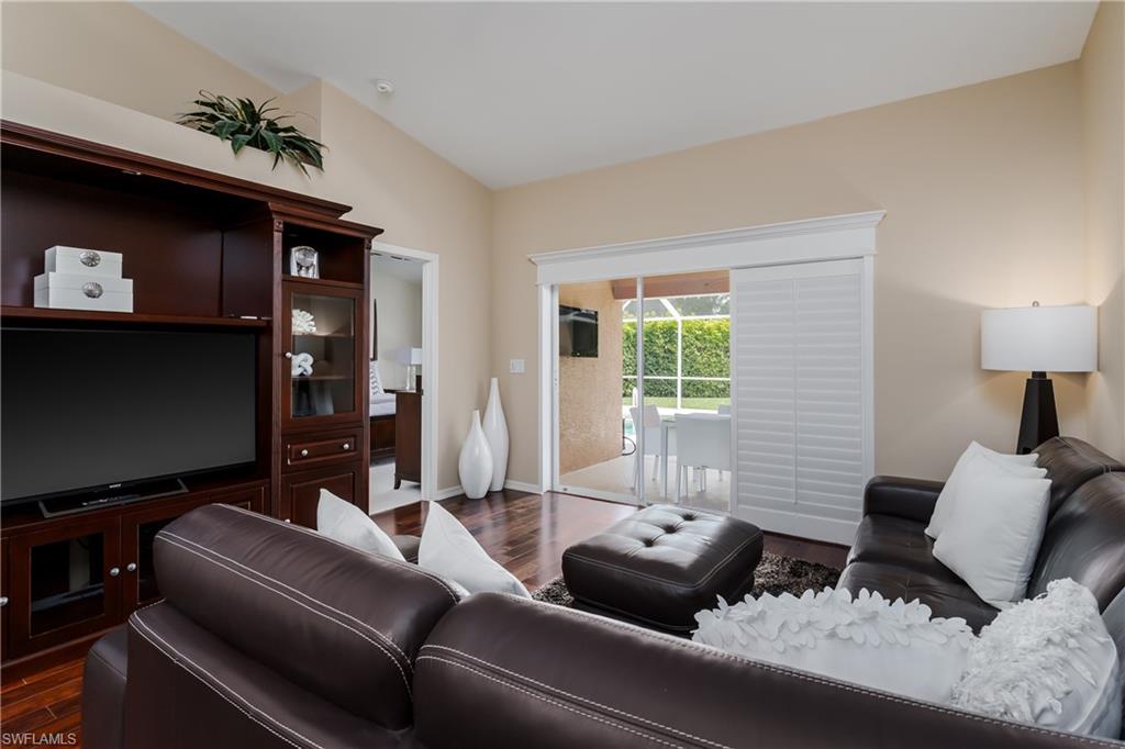 6658 Castlelawn Place, Unit 9 Naples, FL 34113 - Photo 13 of 38 Open-concept living area featuring wood-finish flooring, a vaulted ceiling, and a contemporary drum pendant light
