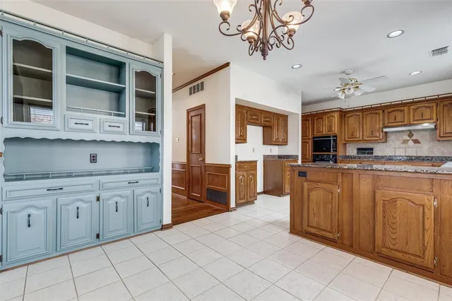 a kitchen with stainless steel appliances granite countertop a refrigerator oven a sink dishwasher and white cabinets with wooden floor