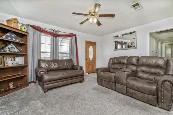 a living room with furniture ceiling fan and a window