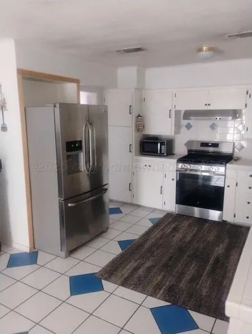 a kitchen with stainless steel appliances granite countertop a refrigerator a stove and a sink