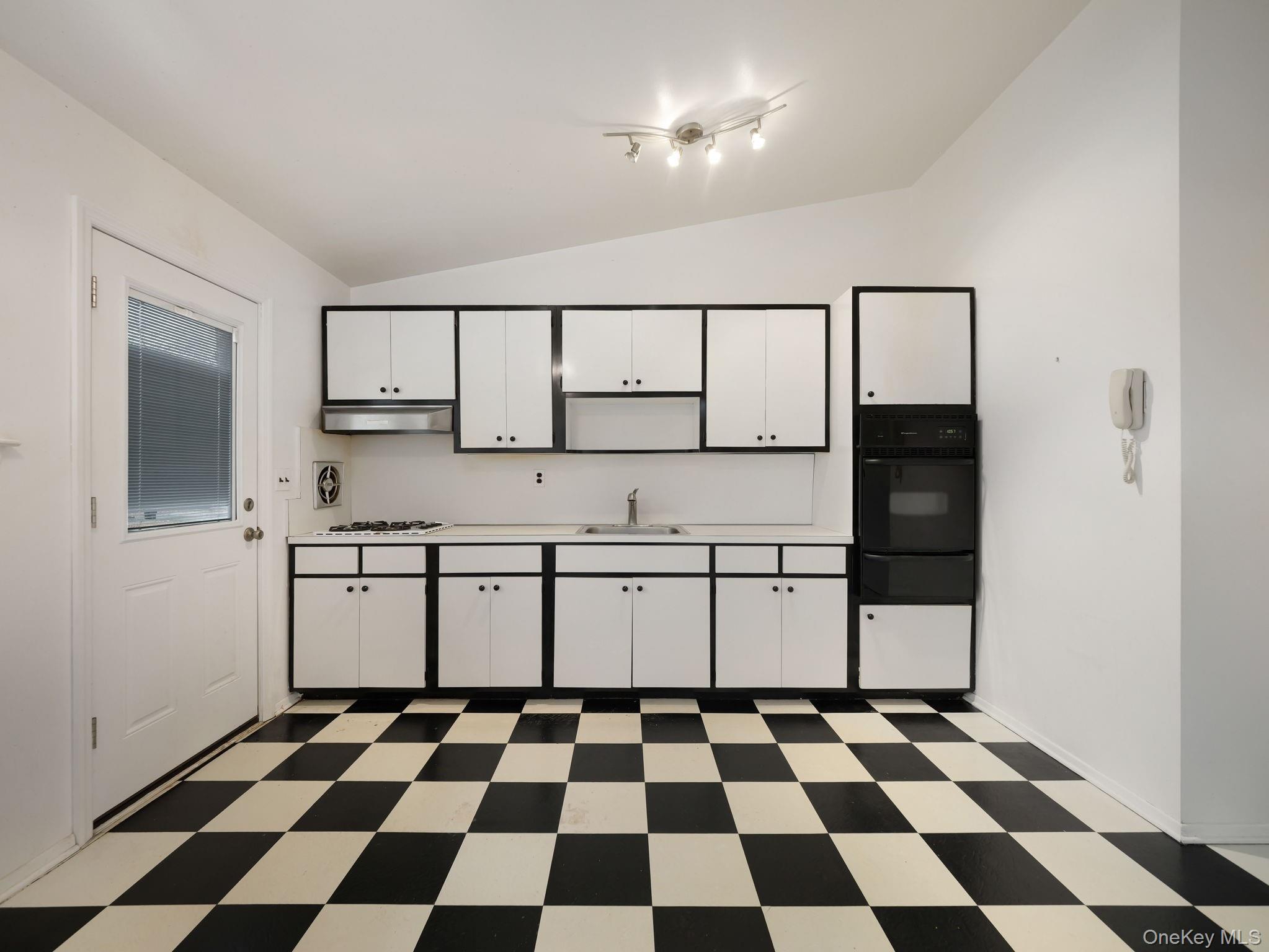 6 Pennington Way Spring Valley, NY 10977 - Photo 14 of 34 Kitchen with vaulted ceiling, light countertops, white cabinetry, and dark flooring