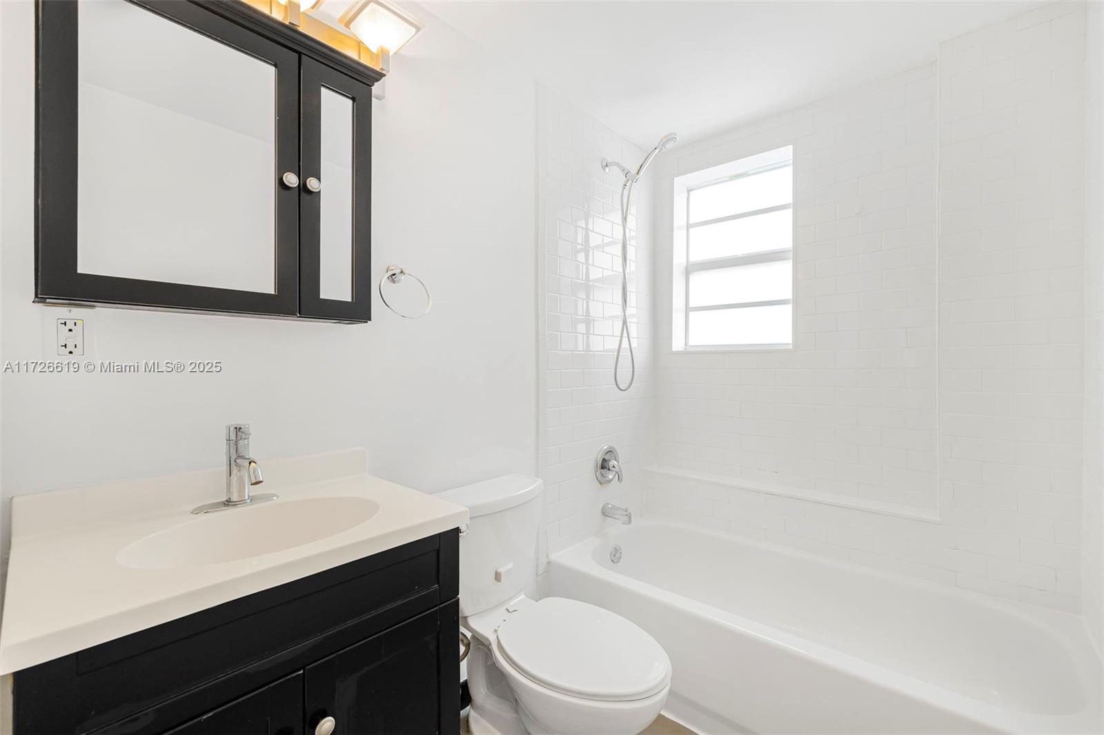 1876 Southwest 11th Terrace, Unit 302 Miami, FL 33135 - Photo 4 of 15 a bathroom with a toilet a sink a mirror and a bathtub
