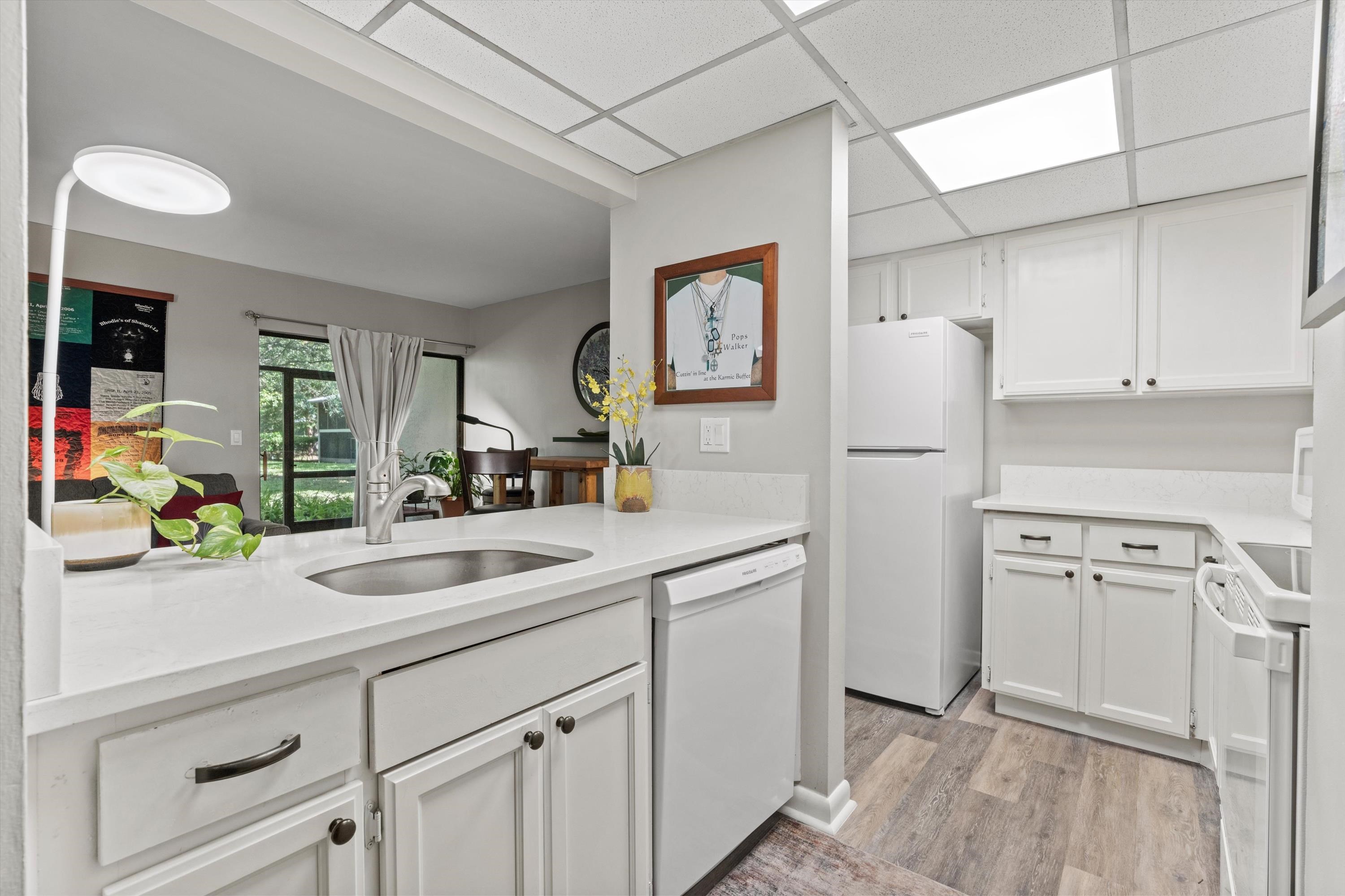 13 Alcira Court St. Augustine, FL 32086 - Photo 9 of 26 Kitchen with white cabinetry, white appliances, light wood-style flooring, a paneled ceiling, and light stone countertops