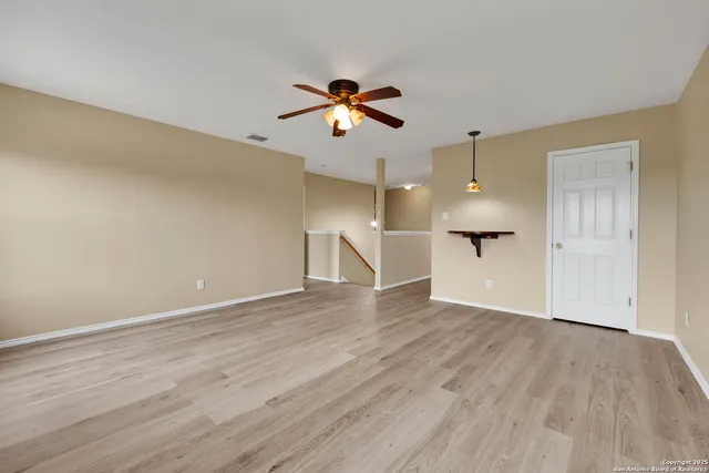 a view of empty room with wooden floor and ceiling fan