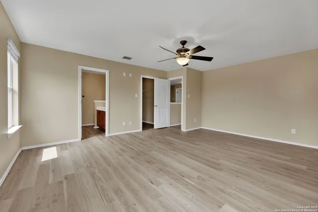 a view of an empty room with a window and a chandelier fan