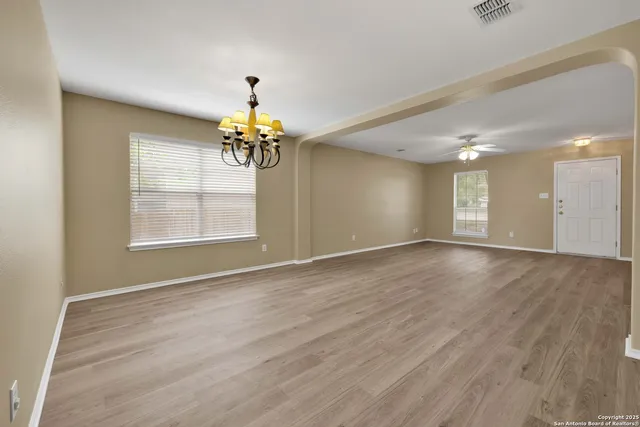 a view of an empty room with a window and wooden floor