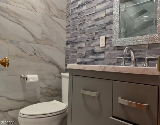 a bathroom with a granite countertop toilet and a sink
