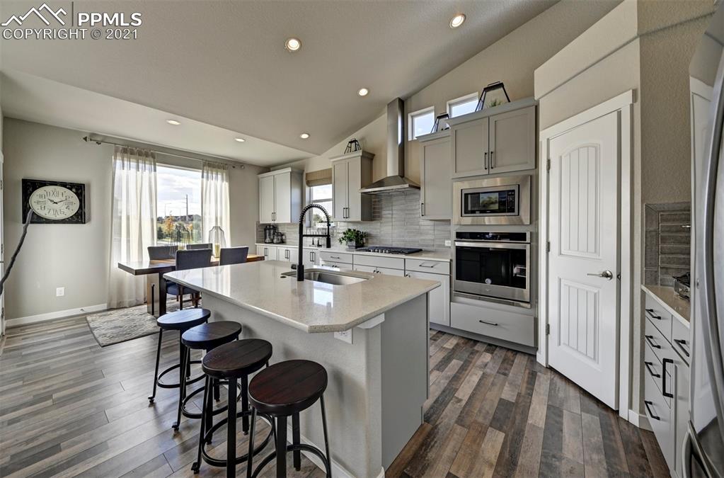 2903 Golden Meadow Way Colorado Springs, CO 80908 - Photo 12 of 49 a kitchen with stainless steel appliances a sink a stove a refrigerator cabinets and a dining table with wooden floor