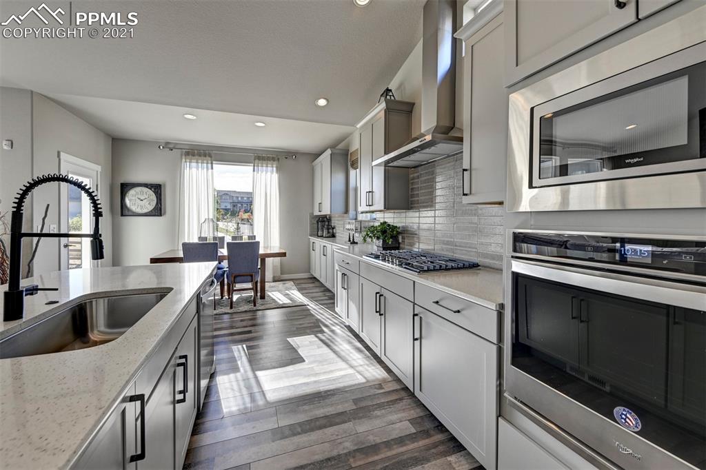 2903 Golden Meadow Way Colorado Springs, CO 80908 - Photo 13 of 49 a kitchen with stainless steel appliances granite countertop a stove top oven a sink dishwasher and white cabinets with wooden floor