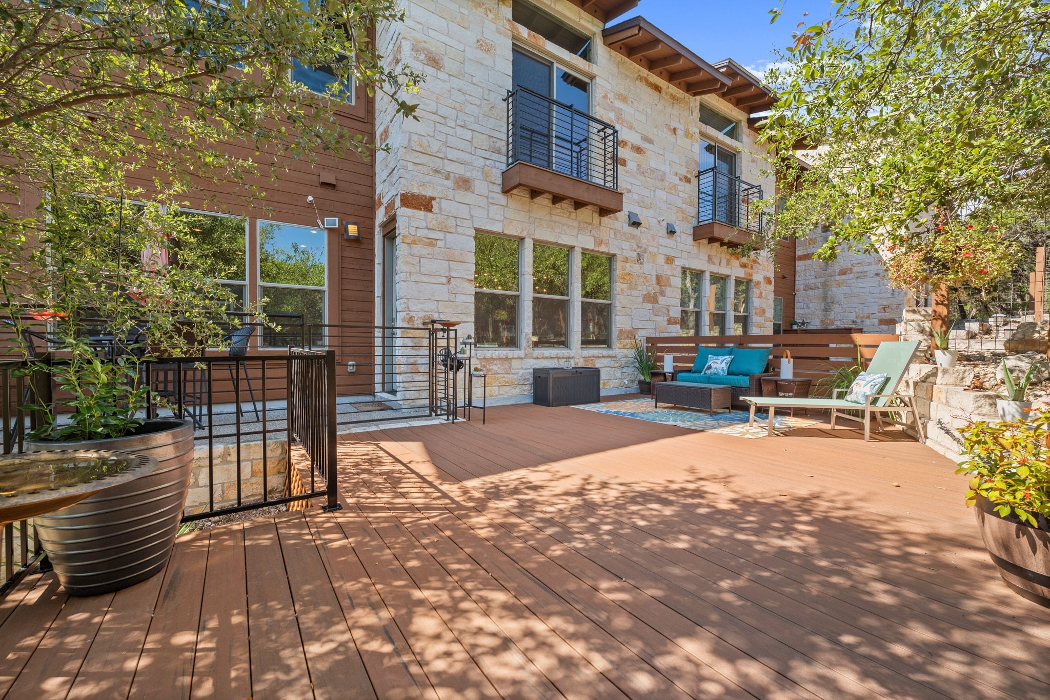 8110 Ranch Road 2222, Unit 92 Austin, TX 78730 - Photo 32 of 40 Expansive wood-finish deck with a stone facade, wood siding, and multiple balconies featuring black metal railings