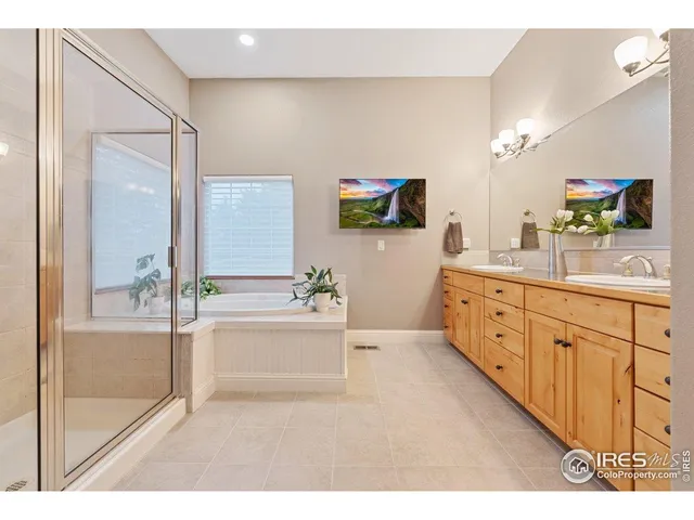 a bathroom with a tub a double vanity sink a mirror and a shower