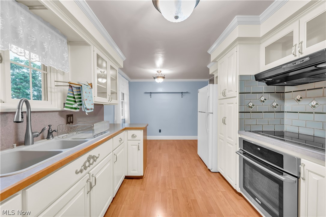 9897 West Ridge Road Elyria, OH 44035 - Photo 15 of 43 Kitchen with white cabinetry, white refrigerator, light hardwood / wood-style flooring, backsplash, and oven