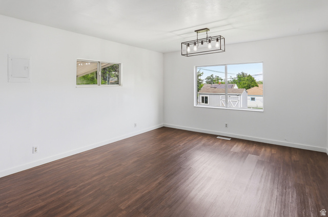 774 37th Street South Ogden, UT 84403 - Photo 4 of 47 Spacious room featuring dark wood-finish flooring, crisp white walls, and a contemporary linear chandelier with exposed bulbs