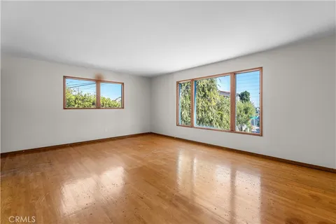 a view of an empty room with wooden floor and window