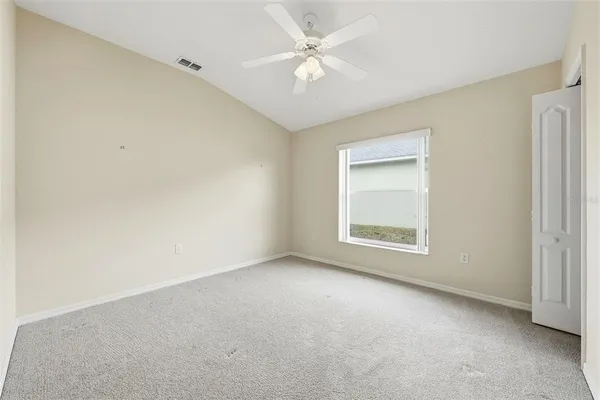 an empty room with chandelier fan and windows