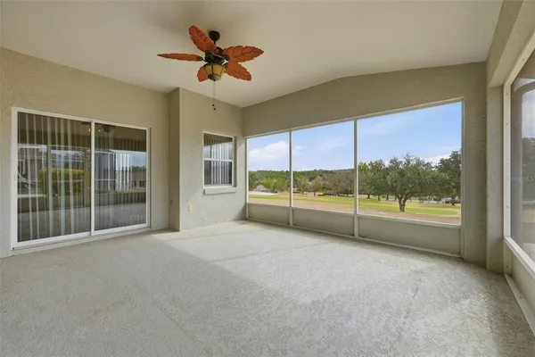 a view of empty room with floor to ceiling window and ceiling fan